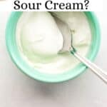Overhead view of bowl of sour cream with a spoon in it on grey surface pin with text overlay.