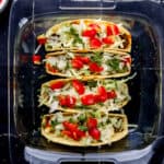Overhead view of tacos topped with chopped cilantro in glass baking dish.