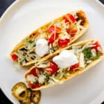 Overhead view of two beef tacos on white plate with slices of jalapeno.
