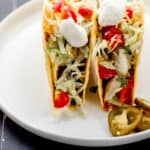 Close up front view of two tacos on white plate.