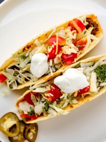 Overhead view of two tacos on white plate.