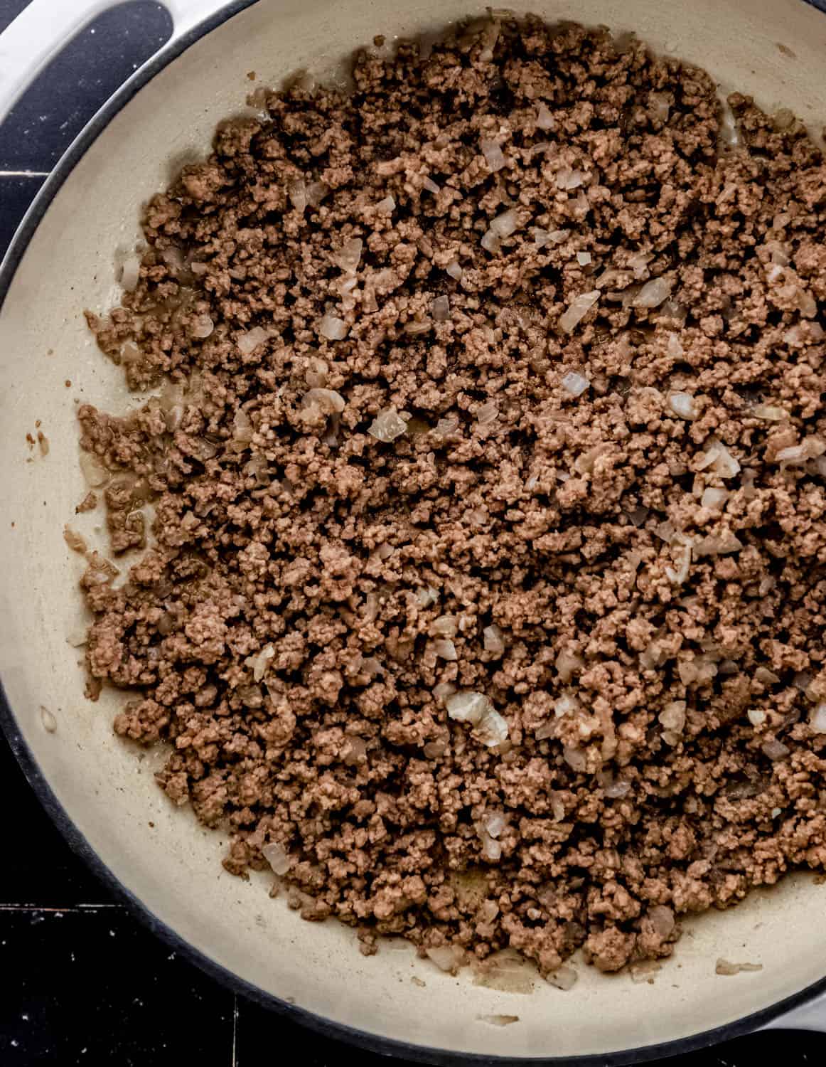 Ground beef and chopped onion in large white braiser pan. 
