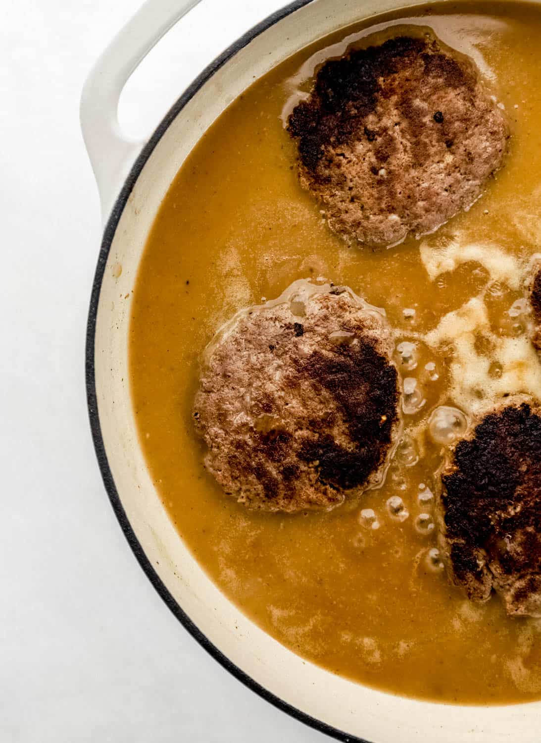Burgers returned to large white braiser pan with gravy. 