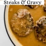 Finished steaks in gravy in pan on pin with text overlay.