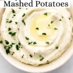 Overhead view of white bowl of mashed potatoes topped with butter and parsley on pin with text overlay.