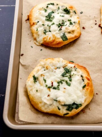 Close up front view of finished pizzas on parchment lined baking sheet.