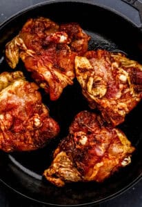 Chicken thighs skin side down in cast iron skillet.