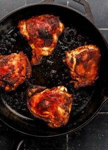 Chicken thighs in cast iron skillet.