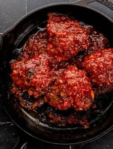 Overhead view of finished bbq chicken thighs in cast iron skillet.