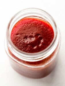 Close up overhead view of sauce in jar on grey surface.