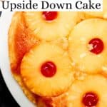 Close up view of pineapple upside down cake on white plate photo on pin with text overlay.