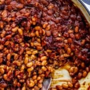 Finished baked beans in braiser pan with serving spoon in it on pin with text overlay.