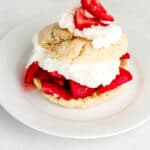 Close up side view of single strawberry shortcake on white plate.