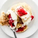Overhead view of single shortcake on white plate with fork cut into it.