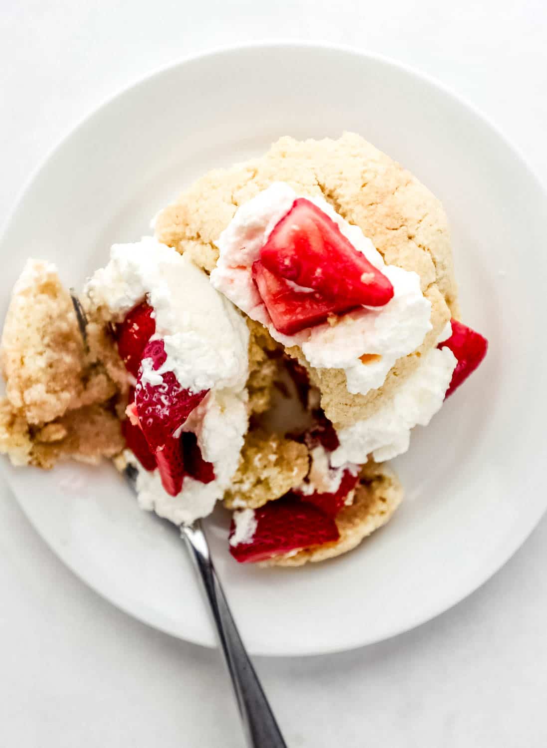 Overhead view of shortcake on white plate with fork in it.