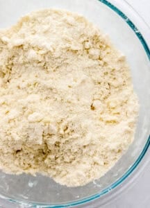 Butter added to dry shortcake ingredients in glass bowl.