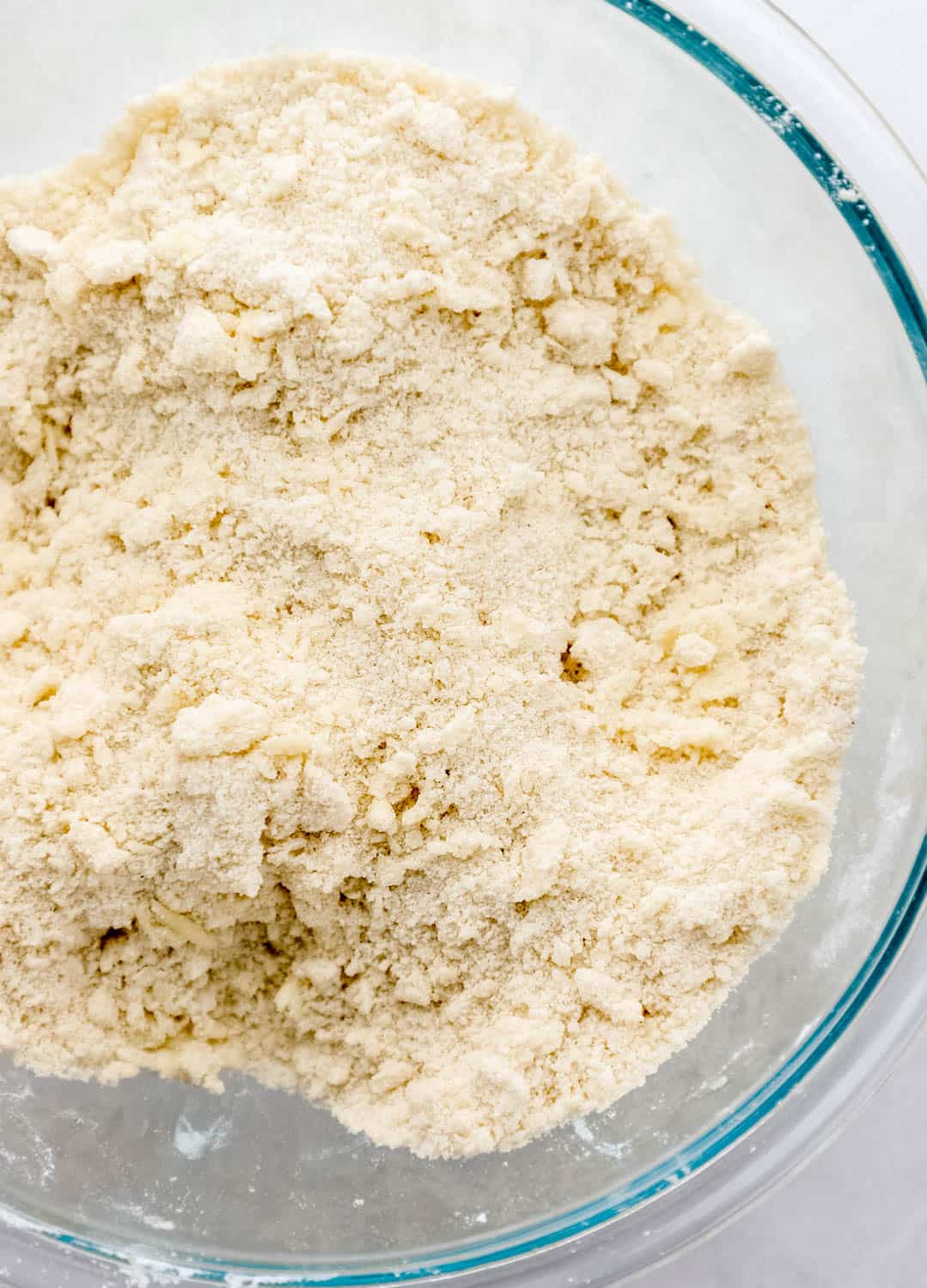 Butter added to dry cake ingredients in large glass mixing bowl.