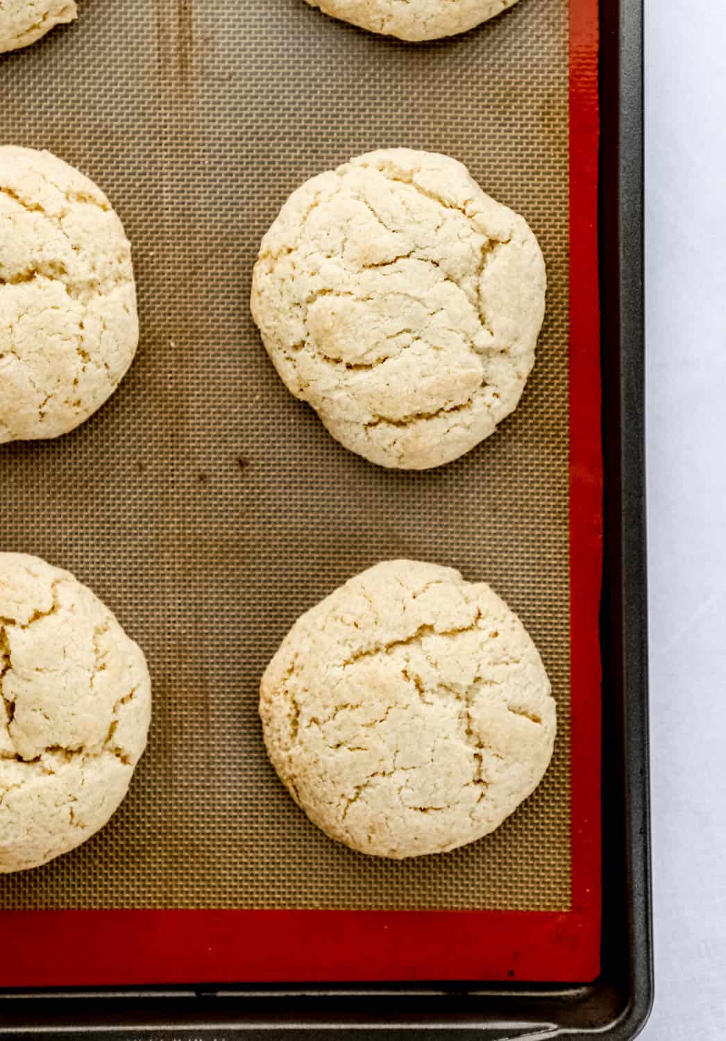 Overhead view of baked shortcakes on large baking sheet with nonstick liner.