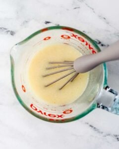 Wet ingredients combined with whisk in glass measuring cup.