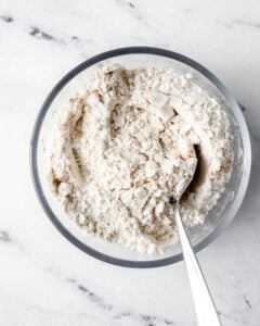 Dry ingredients for muffins in glass mixing bowl with spoon.