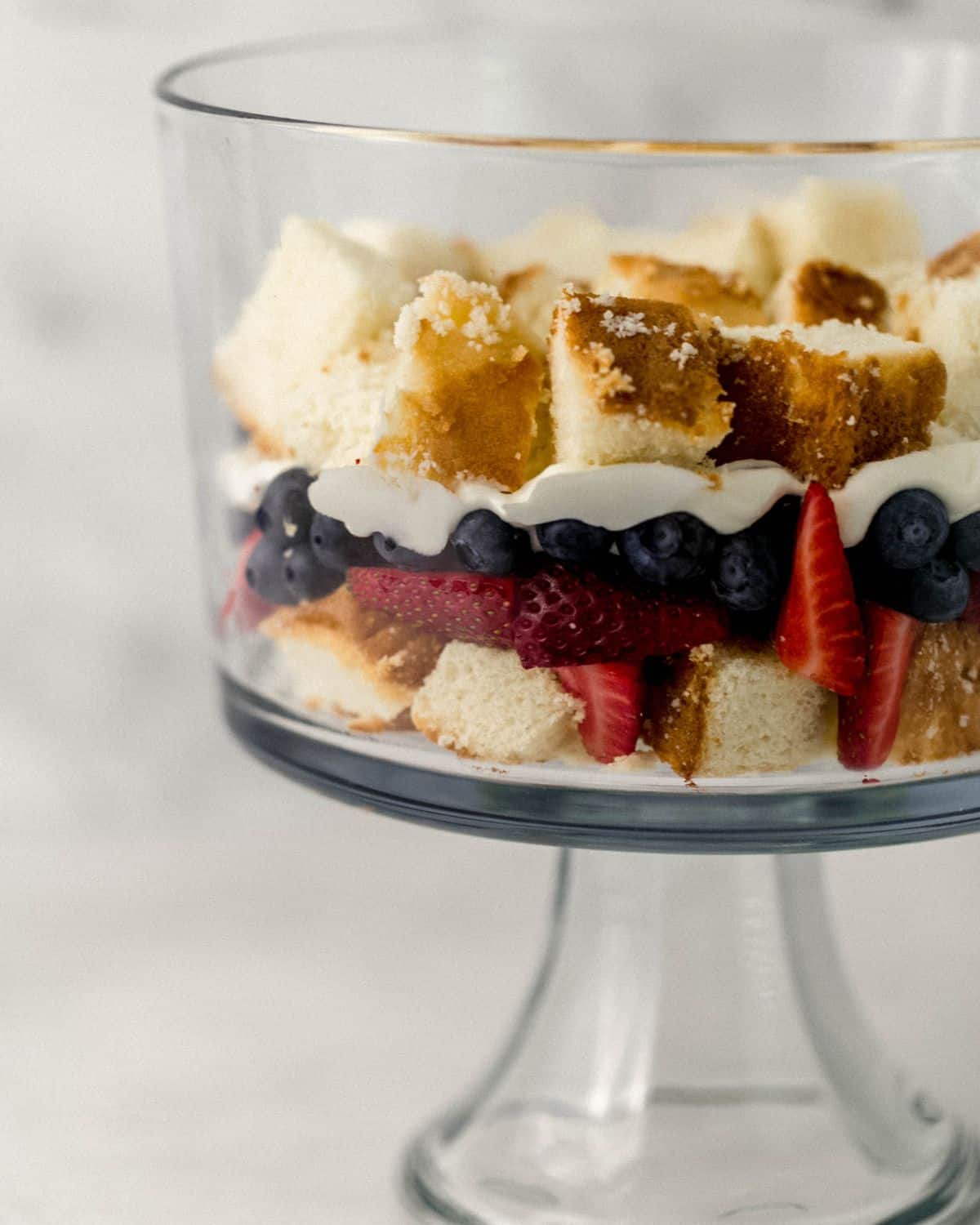 Close up side view of layers of trifle being put in glass trifle dish. 