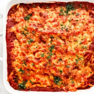 Overhead view of finished casserole topped with chopped parsley in white baking dish.