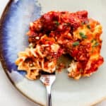 Serving of casserole on a plate with a fork in it.