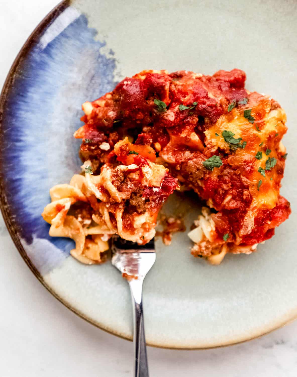 Overhead view of serving of casserole on a plate with a fork in it. 