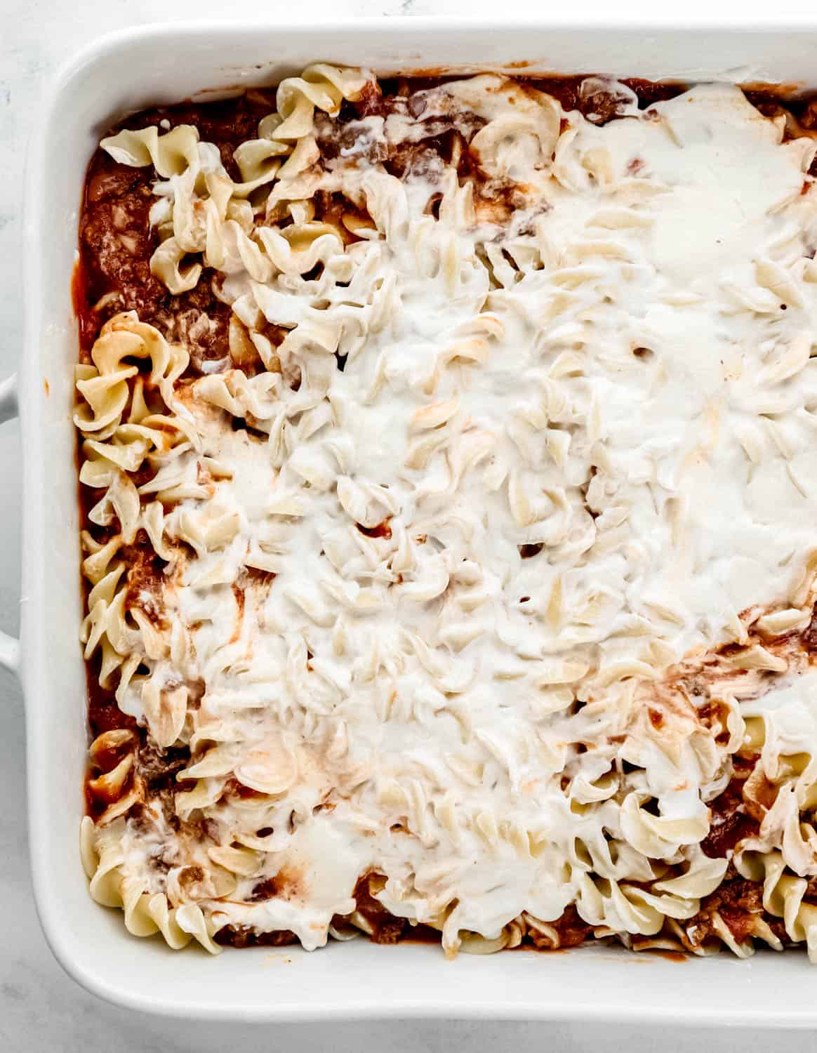 Noodles and cream cheese sauce added to baking dish with the other ingredients. 