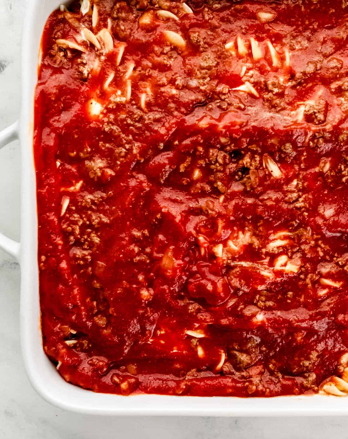 Overhead view of meat sauce added to the casserole dish. 
