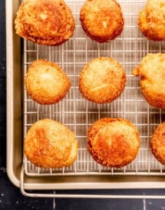 Hush puppies draining on wire rack on top of sheet pan.