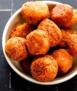 Close up view of hush puppies in large white bowl.