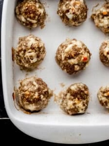 Overhead view of baked meatballs in white baking dish.