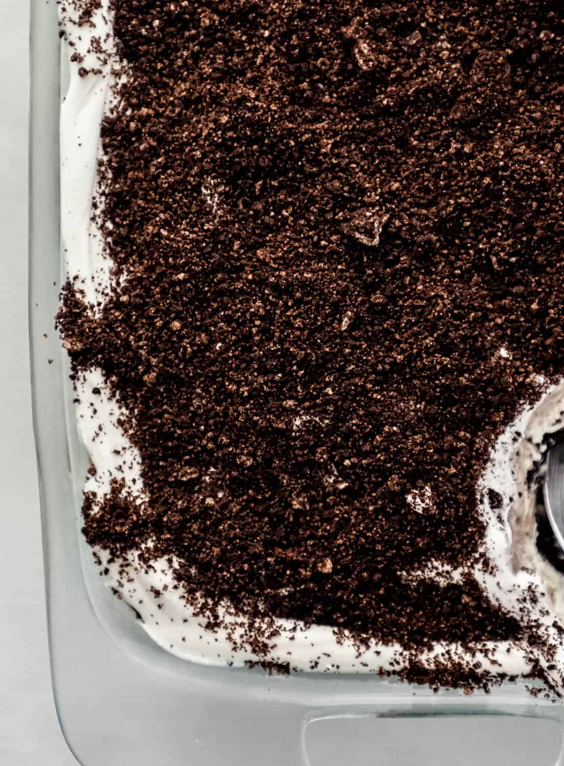 Close up view of finished oreo delight in glass dish with serving spoon in it. 