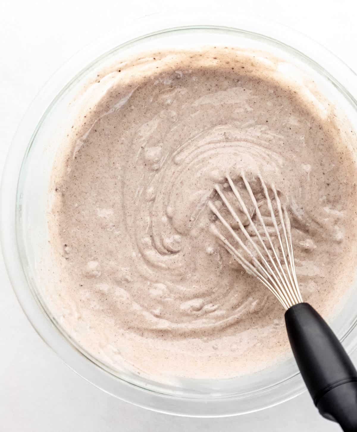 Pudding mix and milk combined in large glass mixing bowl with a whisk. 