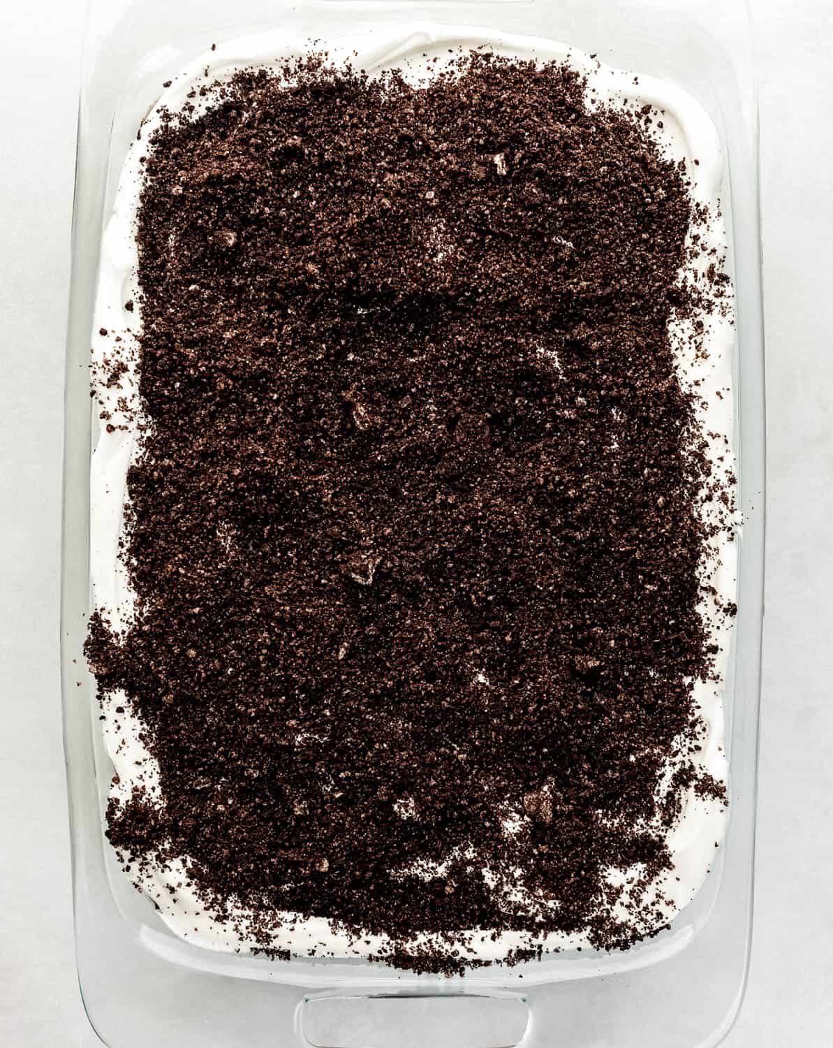 Crushed cookie crumbs added to the top of the delight dessert in the glass dish. 