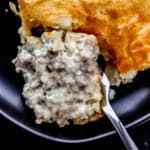 Close up overhead view of serving of casserole on black plate with a fork cutting into it.