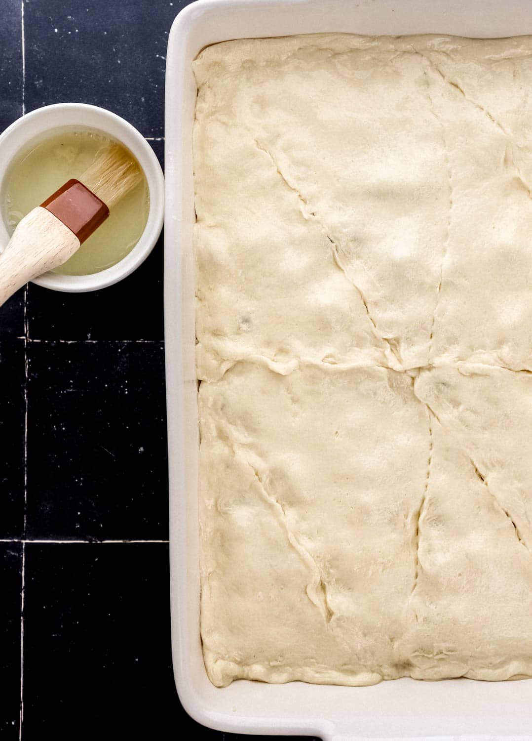 Unbaked casserole in white baking dish topped with an egg wash mixture before baking. 