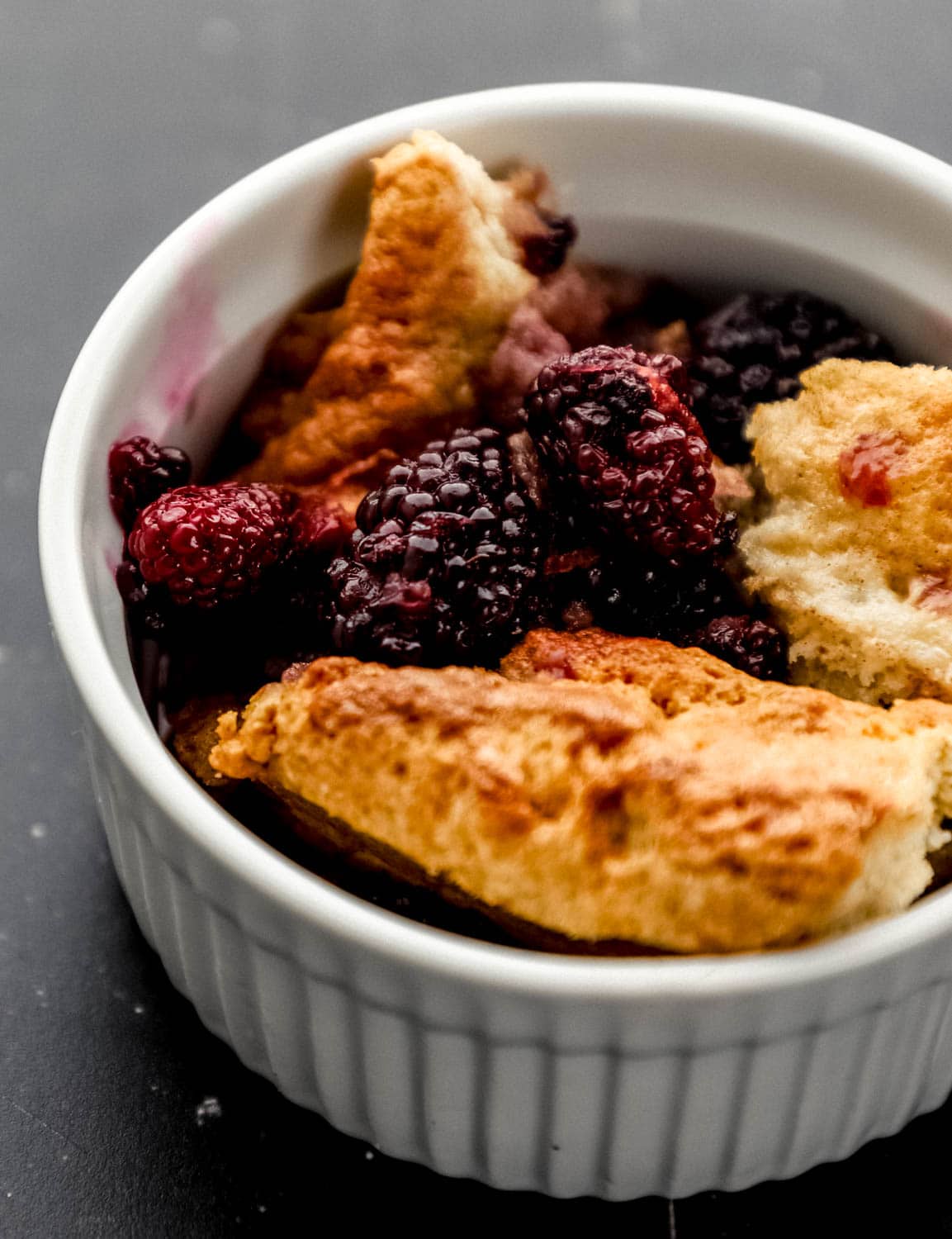 Close up front view of serving of finished cobbler in small white bowl. 