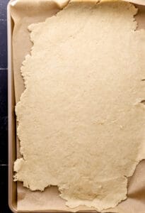 Rolled out dough on parchment lined sheet pan.