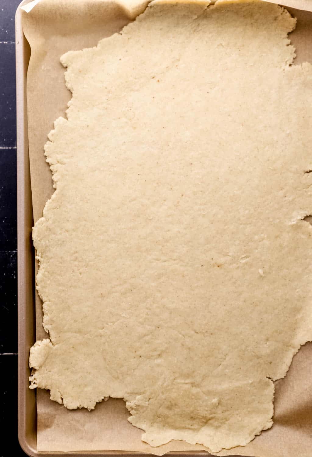 Overhead view of cobbler dough on parchment lined baking sheet. 