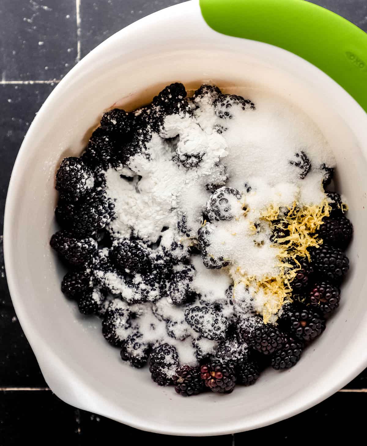 Blackberries, sugar, cornstarch, and lemon zest in large white mixing bowl. 