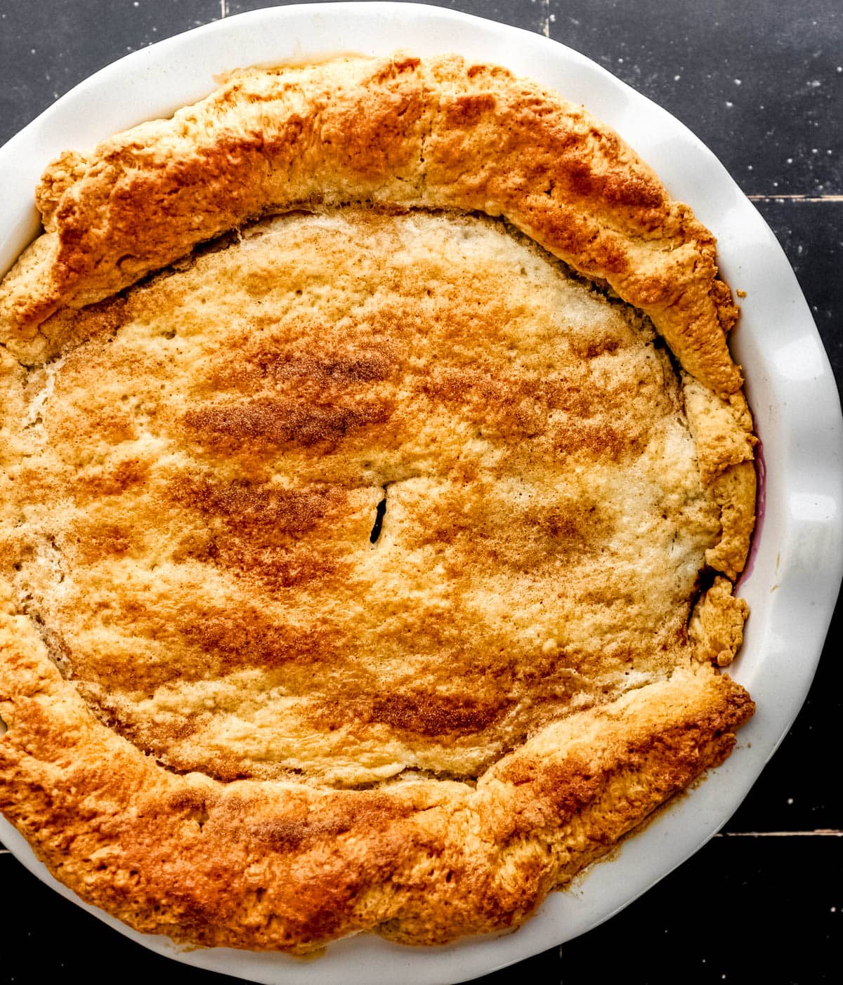 Overhead view of baked cobbler in round white baking dish. 