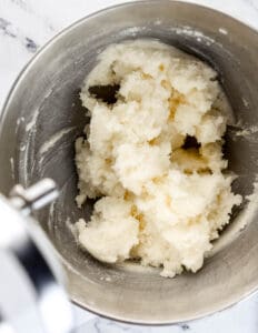 Overhead view of butter, shortening, and sugar combined in stand mixer bowl.