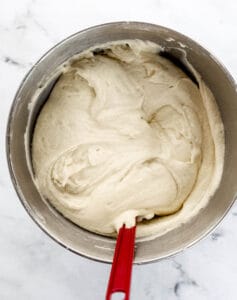 Overhead view of cake mixture in stand mixer bowl with rubber spatula.