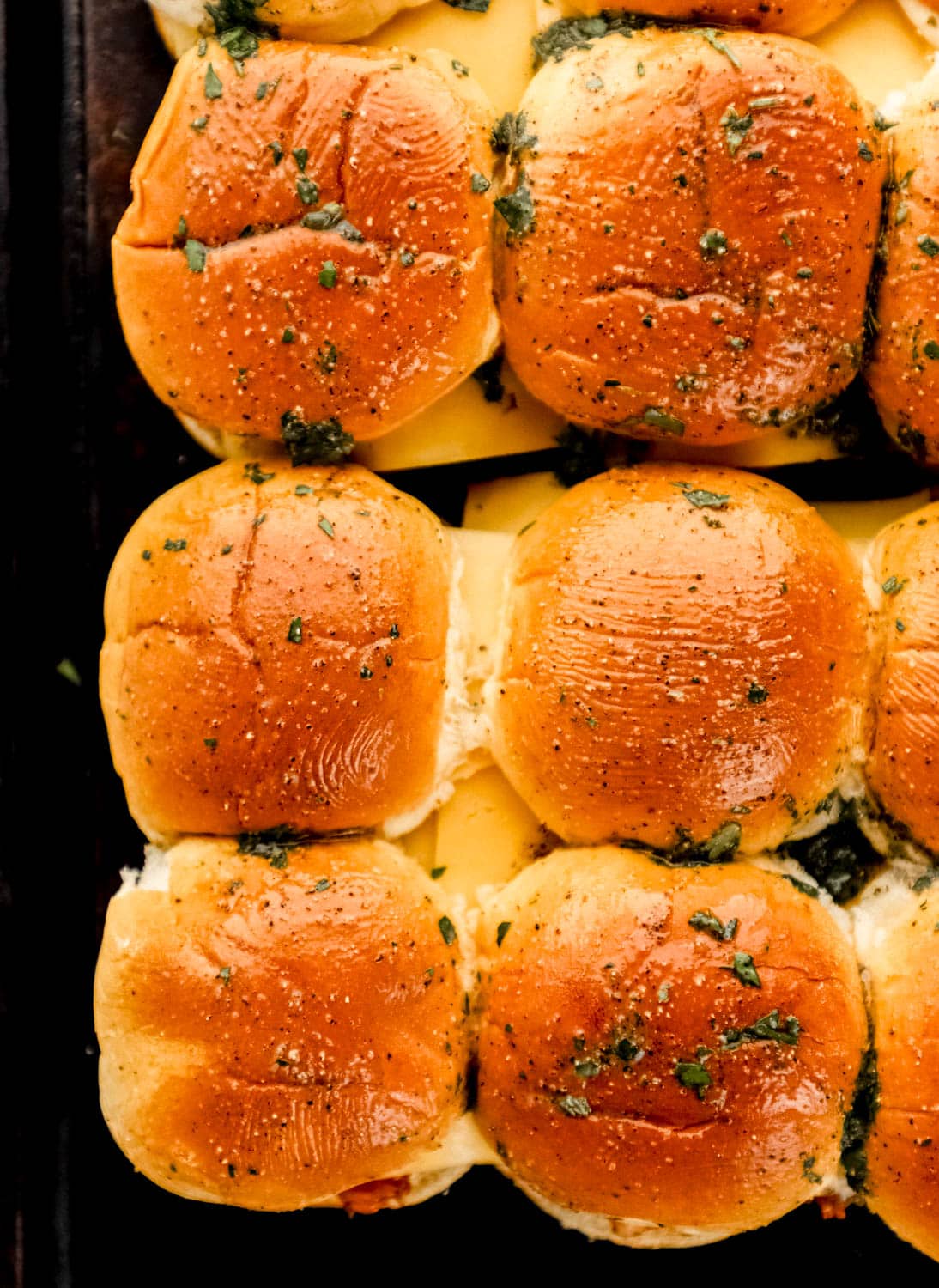 Overhead view of butter mixture added to the top of the slider buns. 