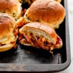Close up view of sliders on sheet pan with one of them cut in half.