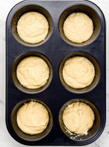 Cornbread mix added to the bottom of a muffin pan.