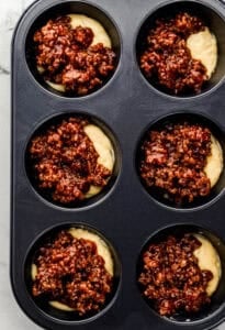 Beef mixture added to muffin mix in muffin pan.