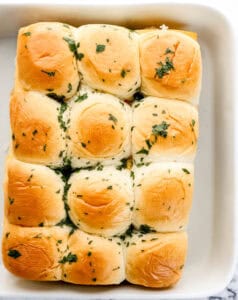 Top half of slider buns added and topped with parsley and melted butter.